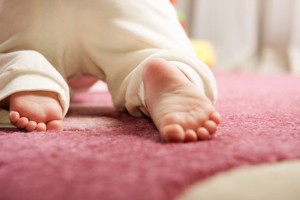 Little baby crawling on the pink carpet. Rear view